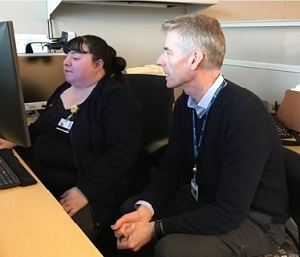 Two people work together at an office computer.