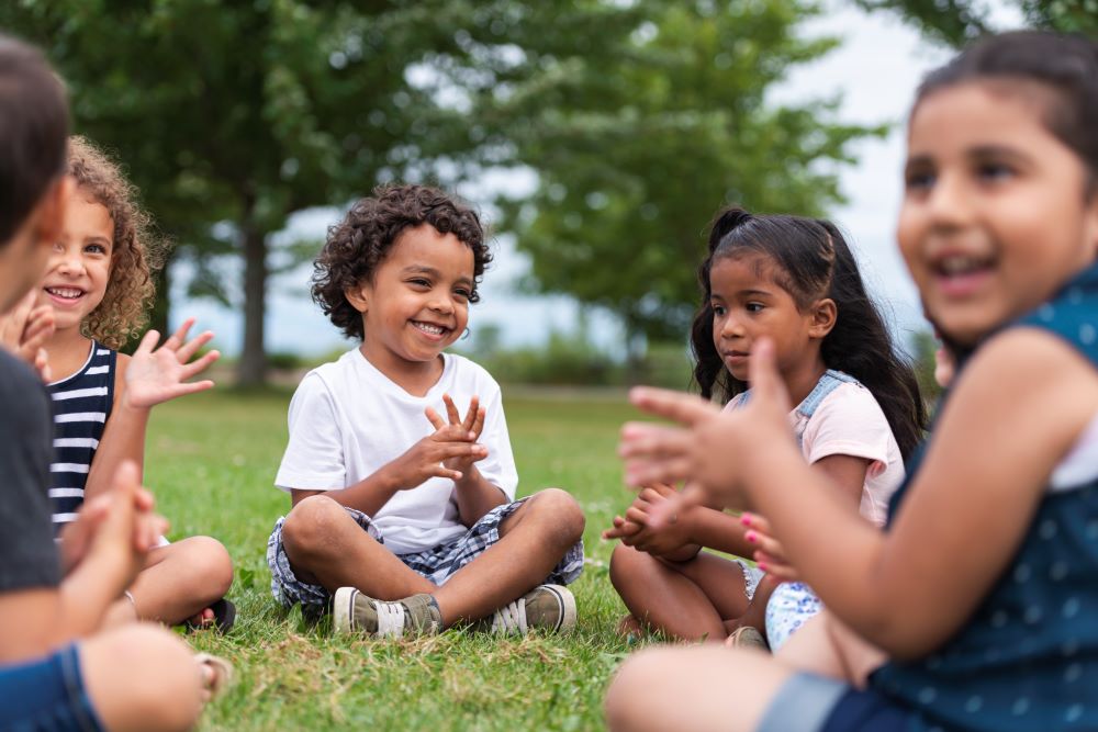 Young children clapping on a lawn