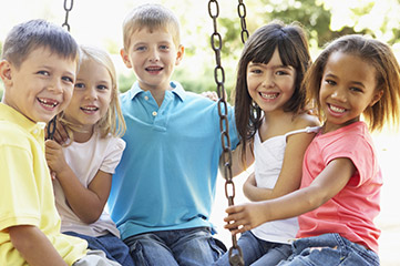 Smiling group of young kids on a swing