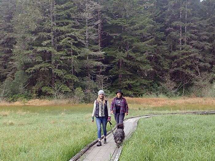 Two people walking on boardwalk with dog