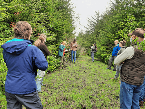 Group of adults stand in semi-circle near trees