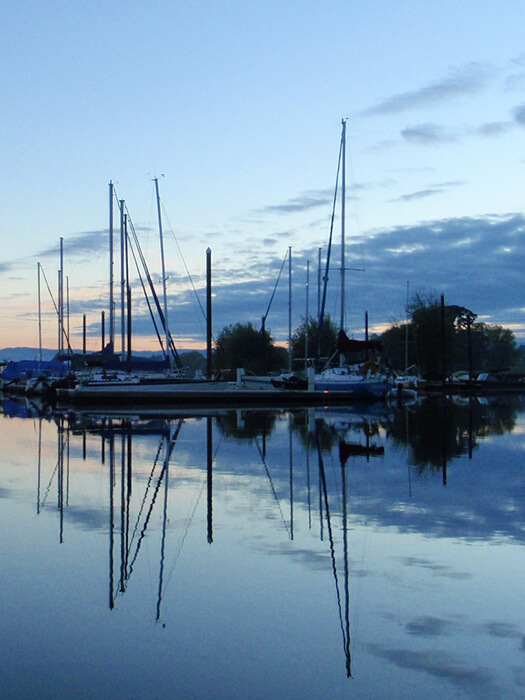 Boats at sunrise reflecting in water.