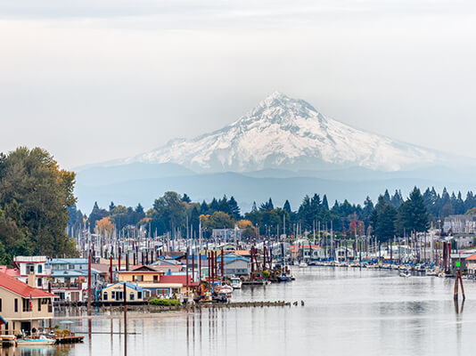 Large mountain with homes on docks in front on water.