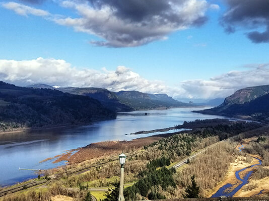 River with mountains on either side and blue sky.