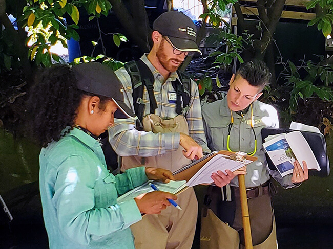 Three people look at a clipboard.