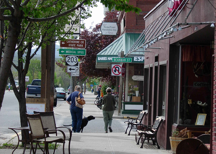 Two women with a dog walk down a city street in Eastern Oregon
