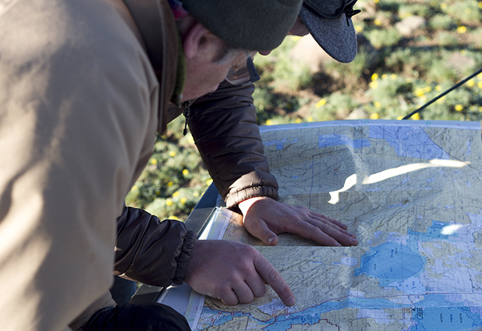 Two people lean over a map outdoors