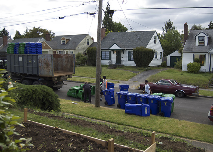 Sanitation workers drop off garbage and recycling buckets.