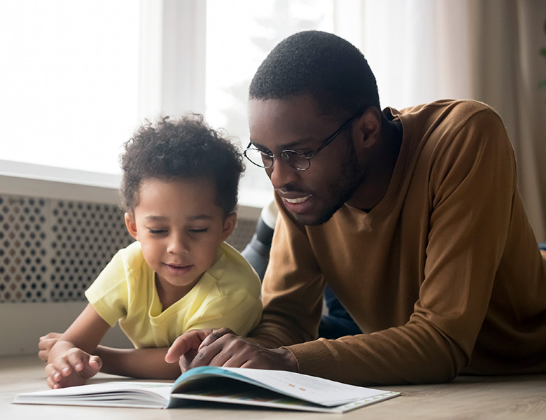 Father and pre-school aged son enjoy a print/braille book together.