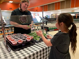 Student sampling strawberries and broccoli