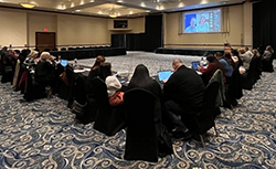 Conference attendees sit together watching a presentation