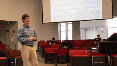 Employee giving a presentation and standing with a projection screen in the background