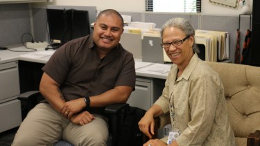 Two employees sitting together smiling at the camera.