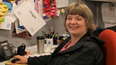Employee sitting at a desk and smiling at the camera