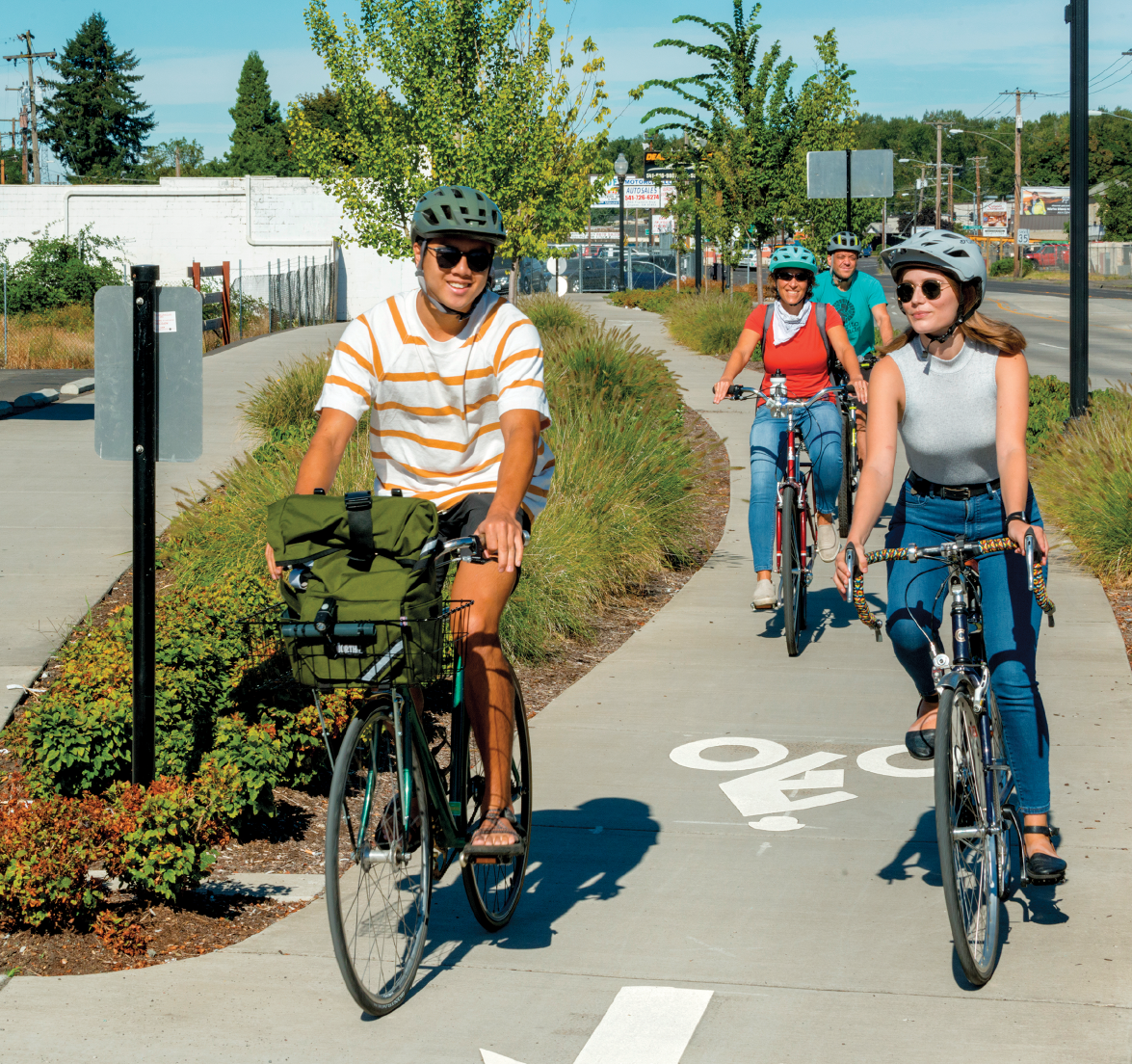 Four people riding bicycles along a marked bicycle path.
