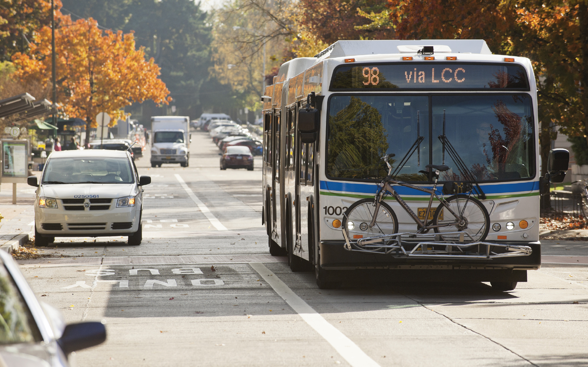 A city bus with a bicycle rack mounted on the front with a bicycle in the rack.