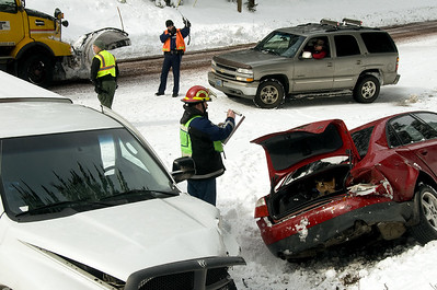 A collision between two cars in the snow with investigators taking notes