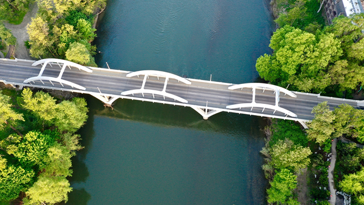 An overhead view of the Caveman bridge, a rainbow arch bridge over the Rogue river in Grantspass, Oregon.