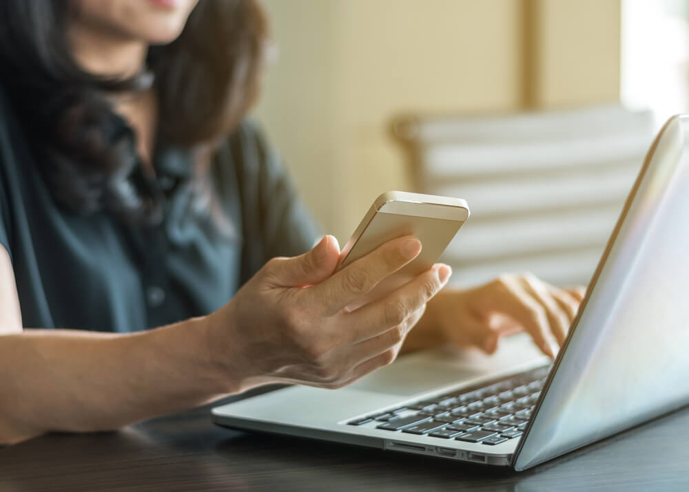 Person using cell phone and computer