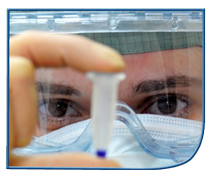 Image of a person wearing protective goggles and face mask examining a test specimen
