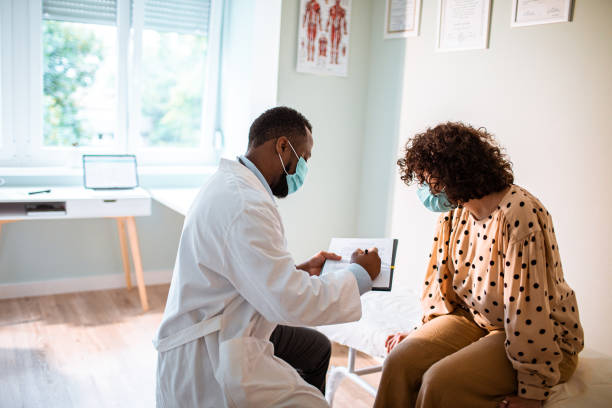 Medical Exam Close up of a doctor doing a medical exam while both him and the patient are wearing protective masks black people stock pictures, royalty-free photos & images
