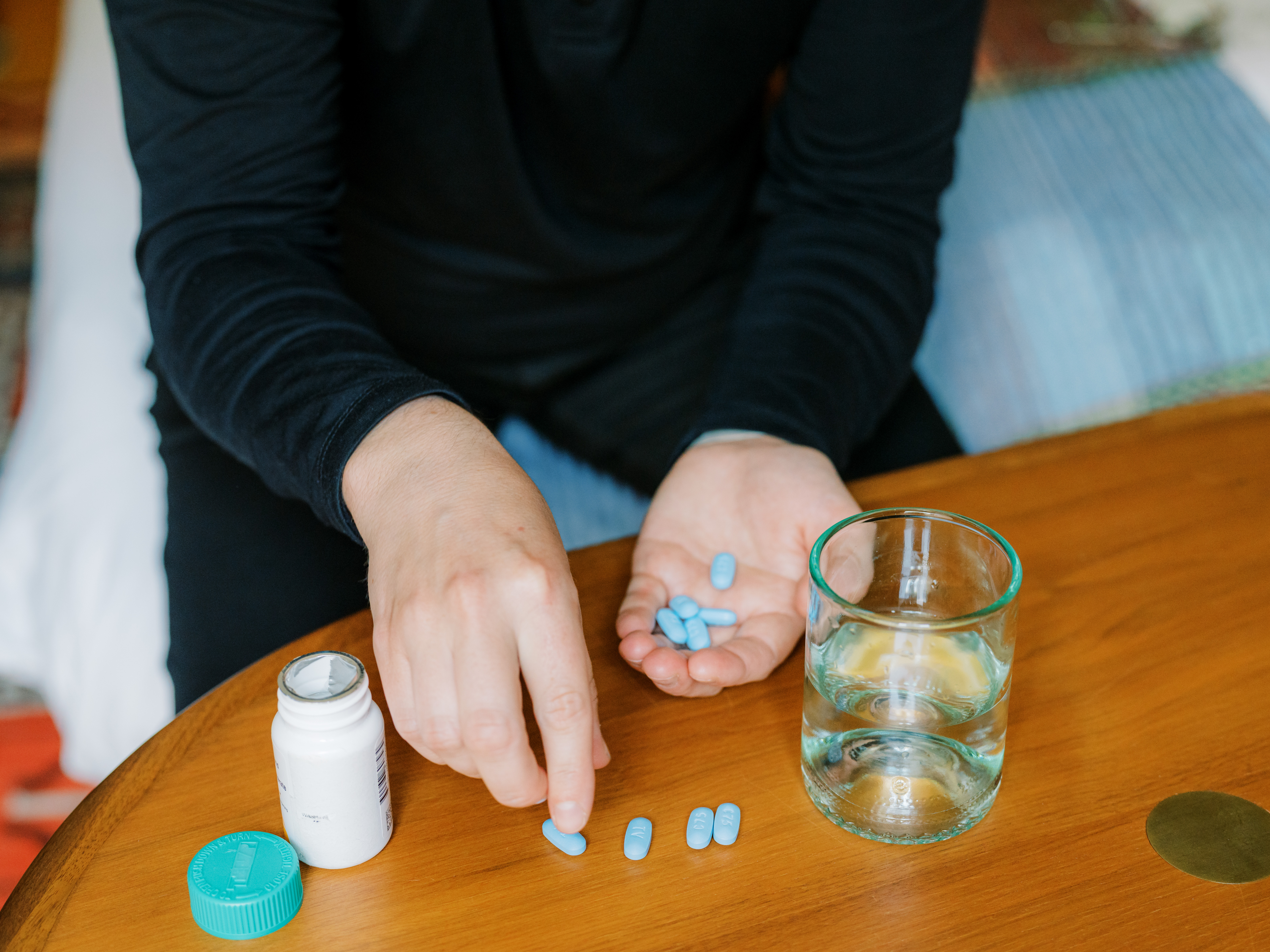 Decorative image - hands sorting pills next to a glass of water and a pill bottle