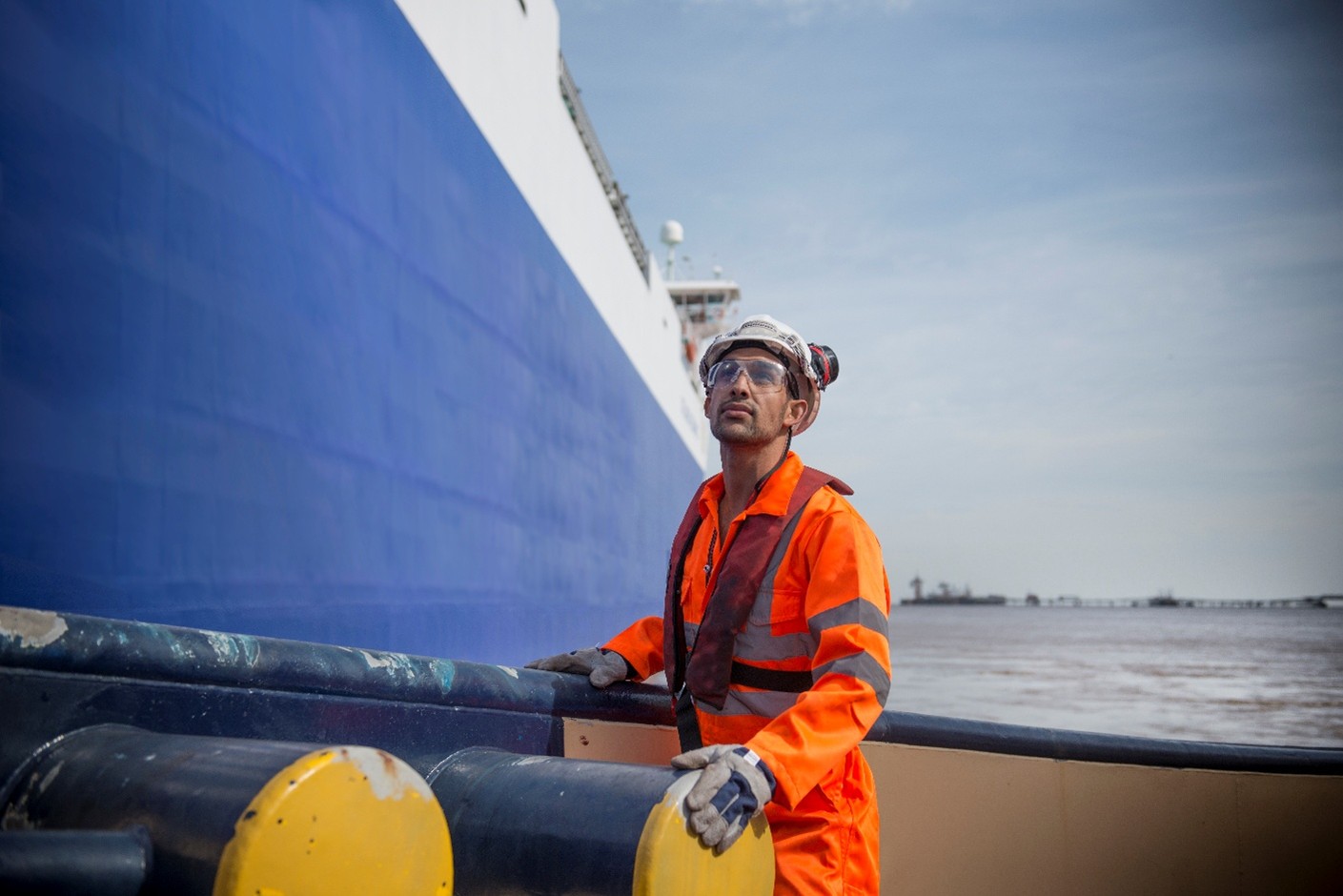 A dockworker wearing safety equipment alongside a ship.