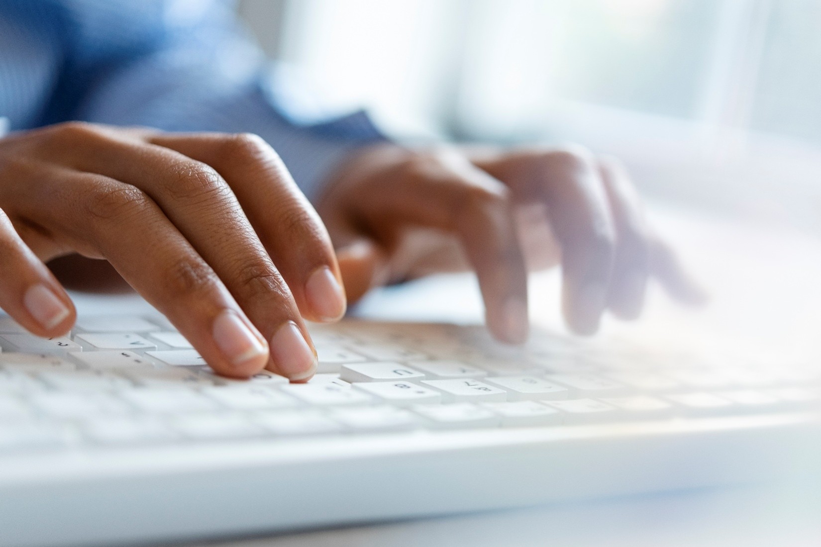 Hands typing on a white keyboard.