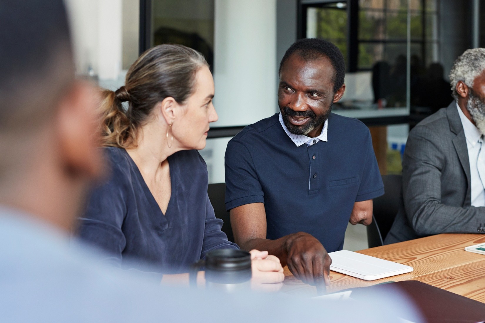 Workers in a meeting together. One of them is an amputee