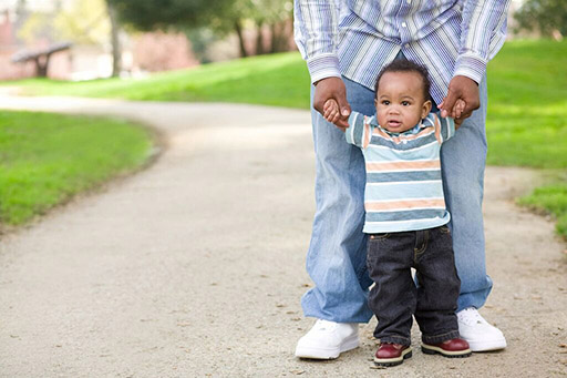 adult holding wrists of child taking steps