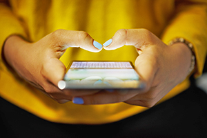 Light up mobile phone being held in a person's hands with thumbs posed as if they are about to type something