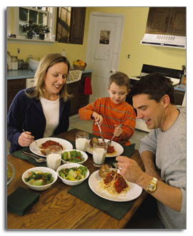Man and woman sitting with a school aged boy eating a meal together 