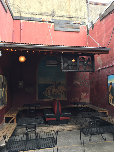 Outdoor seating with a roof and three walls around it with benches and tables