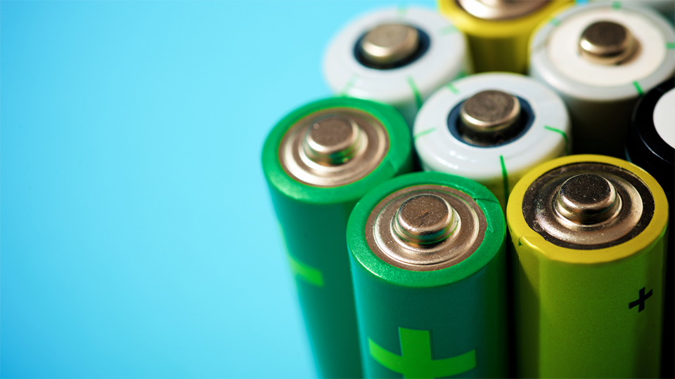 A handful of batteries is standing upright together on a blue background