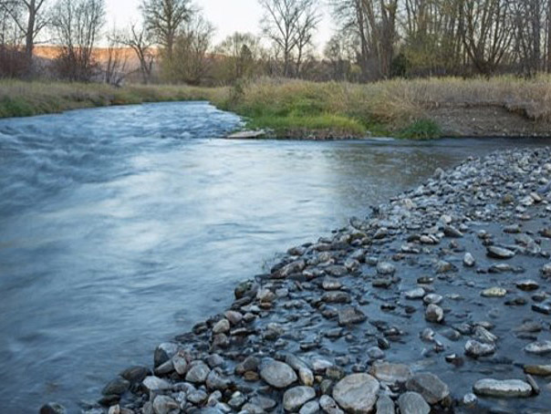 looking at the confluence of the Lostine and Wallowa Rivers as they flow toward the viewer. Large cobble rocks are on the right.