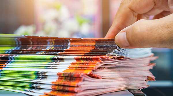 a hand pulling a brochure from a pile