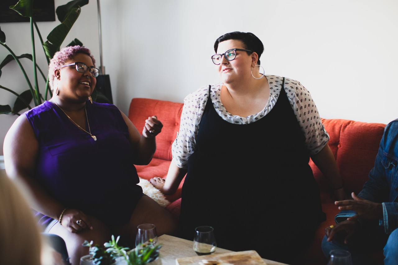two women sitting inside on a couch