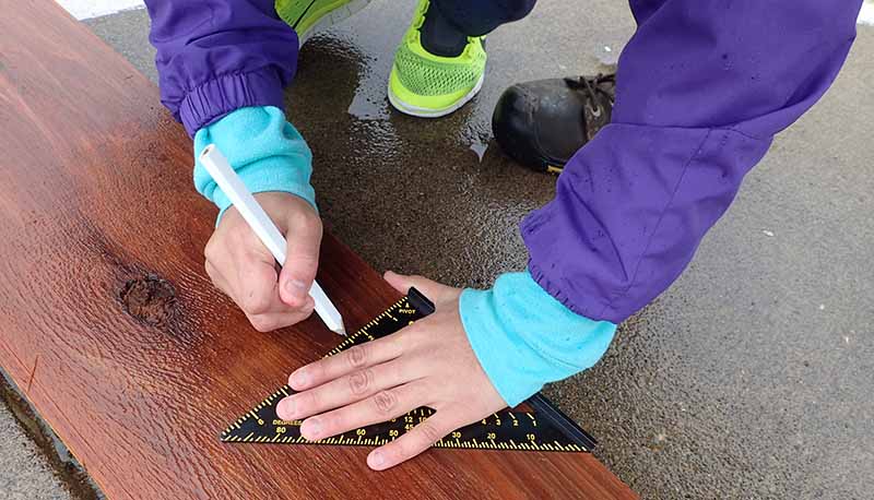 person measuring a board