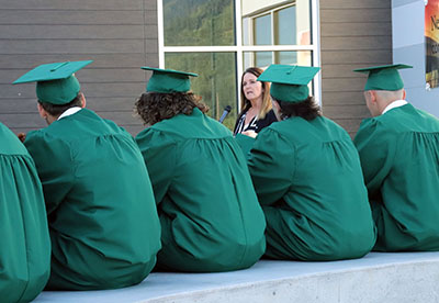 graduates watch woman speak at podium