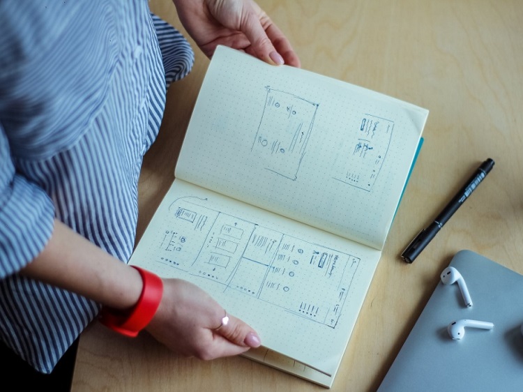 Woman considering drawings in a book.
