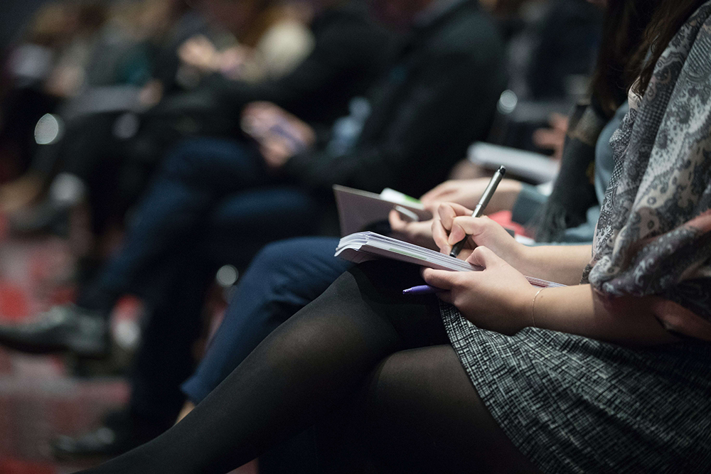 picture of a person jotting notes down at a conference