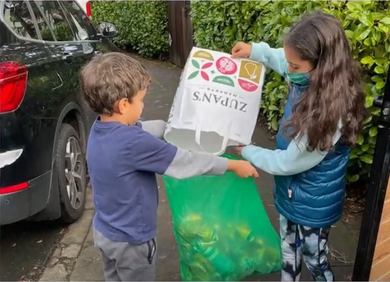 Kids pouring bottles into bottle drop bag
